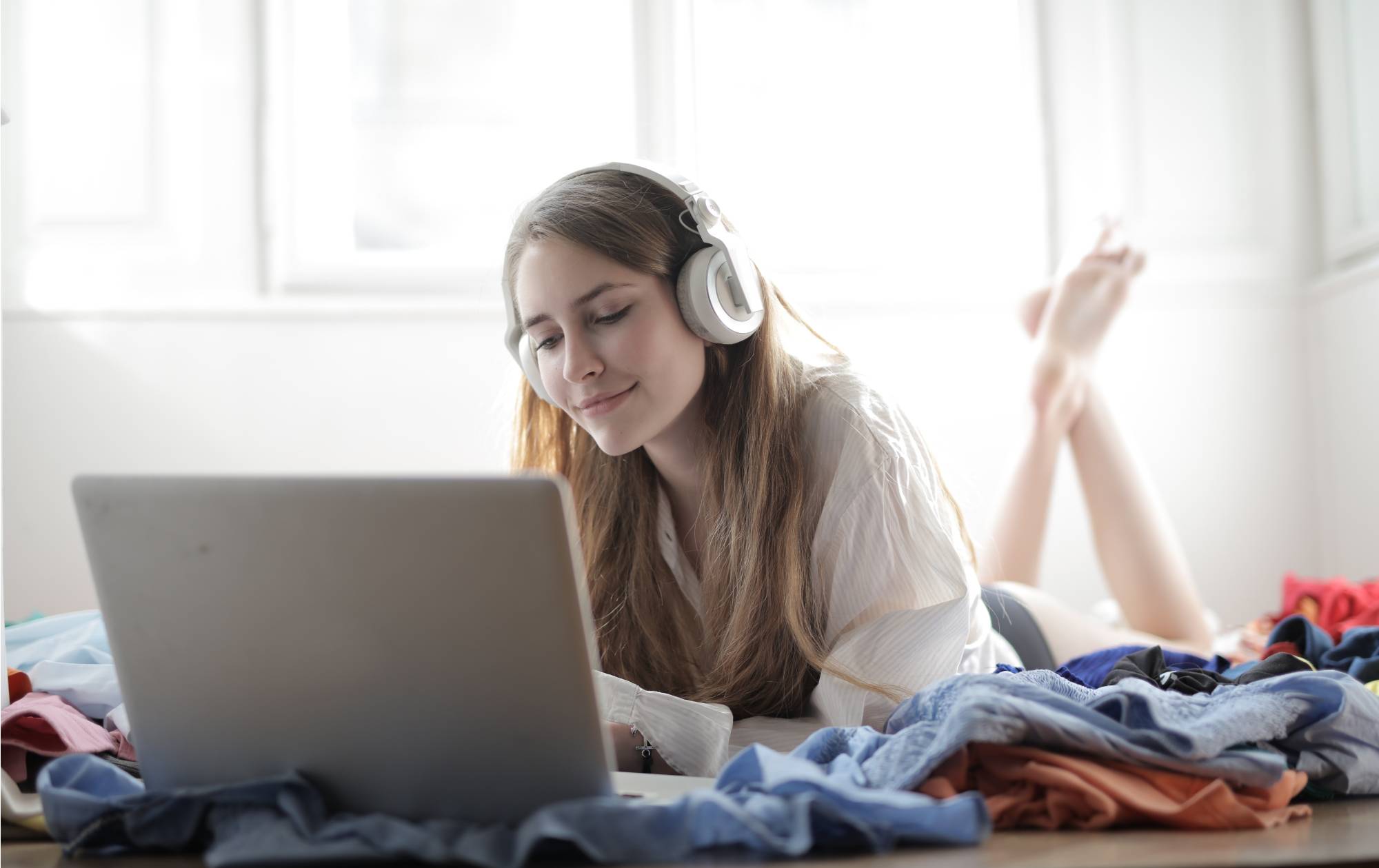 woman listening to audio via headphones while on bed